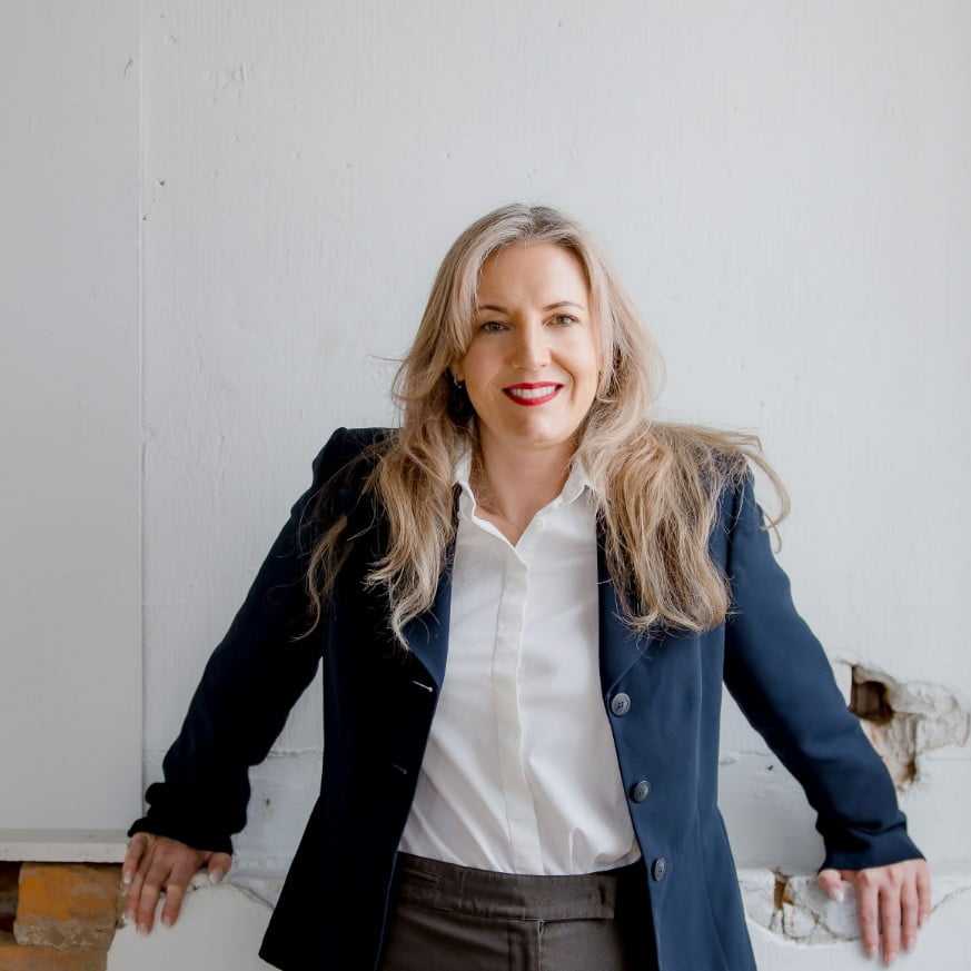 A picture of a business women leaning on a wall.