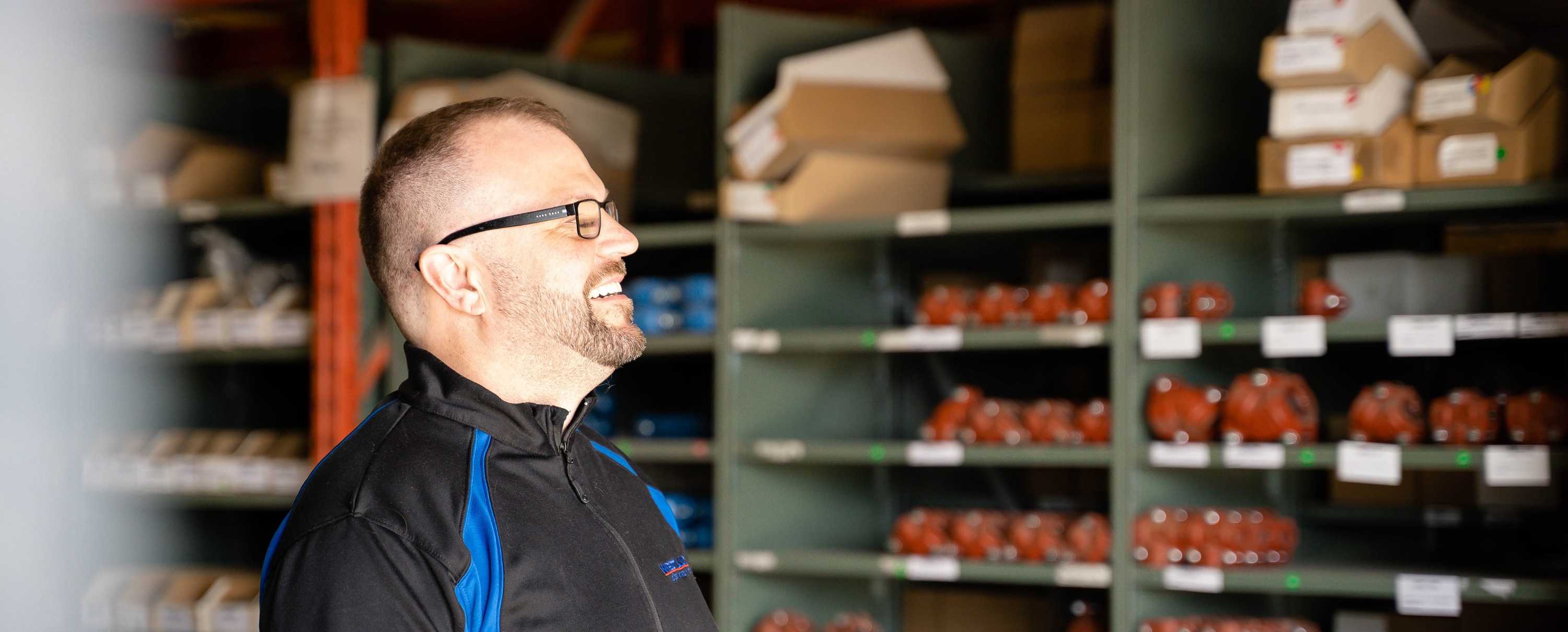 A Picture of a happy worker smiling in a warehouse