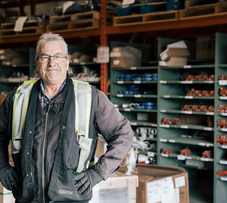 I worker standing in a supply warehouse wearing a safety vest